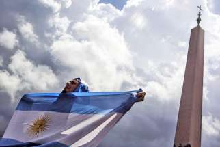 A man holds an Argentine flag at the Vatican in this July 13, 2014, file photo. The sainthood cause of Argentine Cardinal Eduardo Francisco Pironio, who organized the first World Youth Days as president of the Pontifical Council for the Laity, has been forwarded to the Vatican.