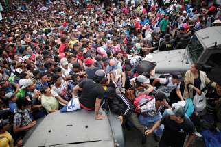 A large group of Honduran migrants, who are part of a caravan trying to reach the U.S., storm a border checkpoint in Tecun Uman, Guatemala, to cross into Mexico Oct. 19. 