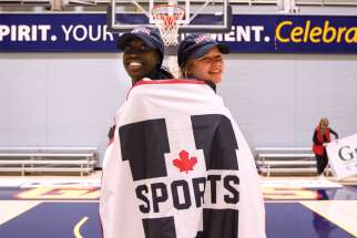 Jama Bin-Edward, left, wraps herself and coach Carly Clarke in the U Sports flag following Ryerson Rams’ national basketball championship earlier this month.