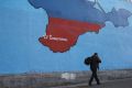 A man passes a mural showing a map of Crimea in the Russian national colors on a street in Moscow March 25. A Ukrainian Catholic priest from Crimea says he fled to Ukraine because Russian authorities are pressuring ethnic Ukrainians.  