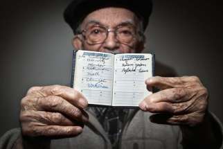 Holocaust survivor Hy Abrams, 90, poses for a portrait Jan. 15 in the Brooklyn borough of New York with a book that documents all the different concentration camps he was held in during World War II. Abrams was taken at age 20 by German Nazi soldiers an d separated from his mother, father, brother and three sisters.