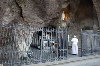 Pope Francis prays at a replica of the Lourdes Grotto in the Vatican Gardens in this 2013 file photo. Pope Francis will pray there May 30, the eve of Pentecost, leading the major shrines around the world in praying the rosary to implore Mary&#039;s intercession and protection amid the coronavirus pandemic.