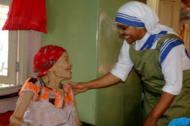 A woman smiles as she is greeted by Sister Marica of the Missionaries of Charity at a home for the elderly in the Pashupatinath temple in Kathmandu, Nepal, July 4.