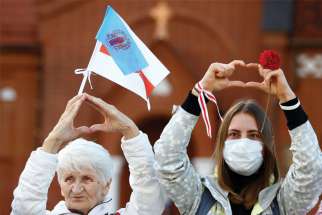 Women gesture in front of Sts. Simon and Helena Church in Minsk Aug. 28, 2020, during a protest against the results of the Belarusian election, which many believe was won by Sviatlana Tsikhanouskaya.
