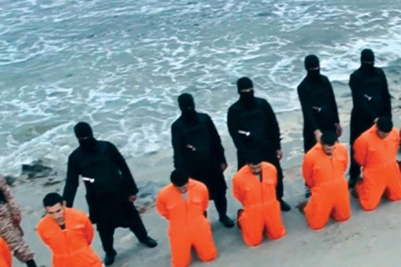 Men in jumpsuits purported to be Egyptian Christians held captive by the Islamic State militants kneel in front of armed men along a beach said to be near Tripoli, Libya, in this still image from an undated video. The video is said to show the beheading of 21 Egyptian Christians kidnapped in Libya.