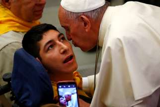 Pope Francis kisses a disabled young man during a special audience with members of Doctors with Africa at the Vatican May 7.