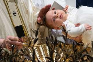 Pope Francis baptizes a baby as he celebrates Mass marking the feast of the Baptism of the Lord in the Sistine Chapel at the Vatican Jan. 9, 2022. The pope baptized 16 infants.