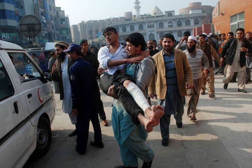 A man carries a student released from a hospital in Peshawar, Pakistan, after the Dec. 16 Taliban attack on the Army Public School. 