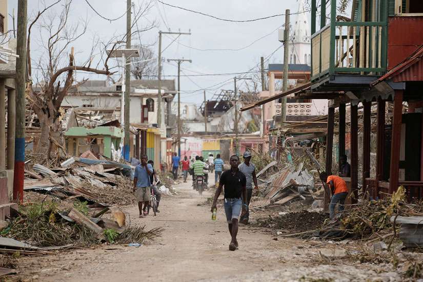 People walk past damaged buildings Oct. 9 after Hurricane Matthew swept through Port-a-Piment, Haiti.