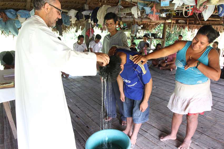 Priest baptizes a young man in a village along the Urituyacu River in Peru June 2014. The Pope recently called for a church with an &quot;indigenous and Amazonian face&quot; during his visit in Peru.