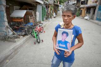 Irma J. Locasia holds a photo of her son Salvador J. Locasia Jr. in Manila, Philippines, Feb. 13, 2019. Her son was killed in a police operation on this street Aug. 31, 2016, a victim of the war on drugs of President Rodrigo Duterte. 