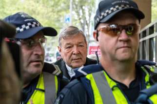 Australian Cardinal George Pell is seen in a 2017 file photo being escorted by police to the Melbourne Magistrates Court.