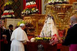 Pope Francis places flowers at a statue of Mary before meeting with clergy, religious men and women, and seminarians at the El Quinche National Marian Shrine in Quito, Ecuador, July 8. 