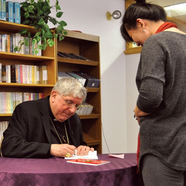 Toronto’s Cardinal Thomas Collins signs a copy of his new book, Cornerstones of Faith, at the archdiocese’s pastoral centre Feb. 20.