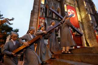 Nuns carry a large wooden cross into St. Joseph&#039;s Cathedral April 14 in Hanoi, Vietnam, to celebrate Good Friday services.