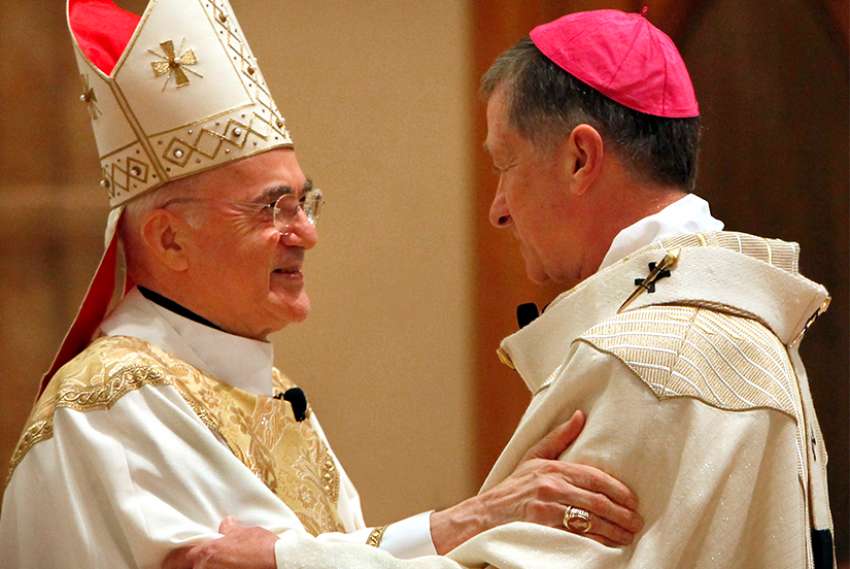 Archbishop Carlo Maria Vigano, then apostolic nuncio to the U.S., left, embraces Archbishop Blase J. Cupich of Chicago after vesting him with the pallium during a special Mass at Holy Name Cathedral in Chicago 2015.