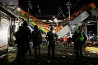 Soldiers stand as rescuers work at a site where an overpass for a metro partially collapsed May 3, 2021, with train cars on it at Olivos station in Mexico City. Picture taken May 4, 2021.