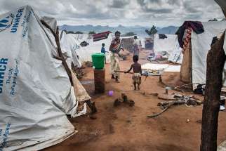 A Mozambican refugee walks towards his mother in Mwanza, Malawi, Feb. 7. Malaria and cold nights add to the suffering of the increasing number of Mozambicans arriving at a makeshift camp in Malawi to escape violence at home, said a church worker in Malawi.