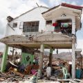 Survivors sit in their damaged house Nov. 10 after Super Typhoon Haiyan battered Tacloban, Philippines. The typhoon, one of the strongest storms in history, is believed to have killed tens of thousands, but aid workers were still trying to reach remote a reas.