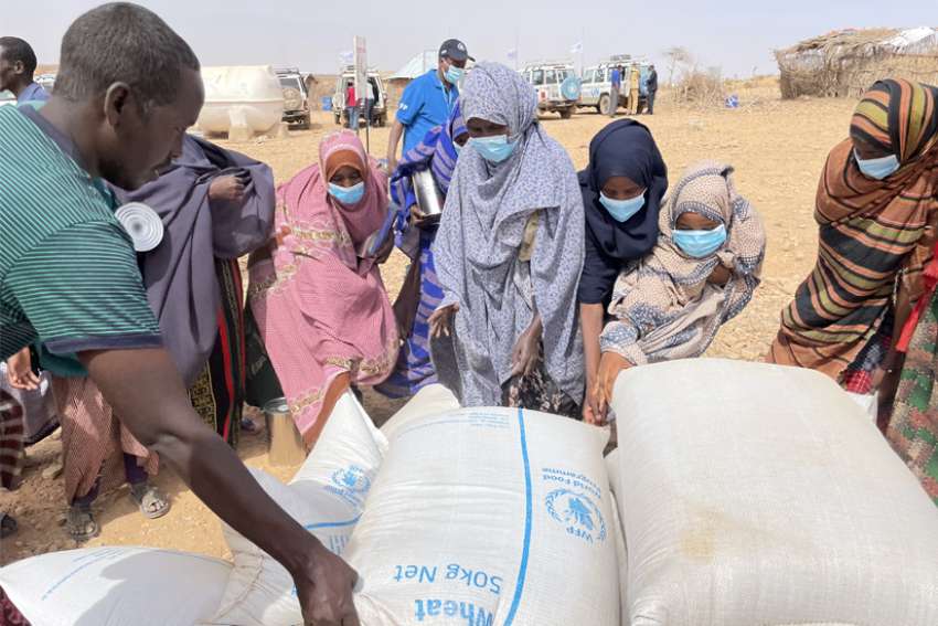 People receive bags of relief grains at a camp for the internally displaced people in Adadle, Ethiopia, Jan. 22, 2022.
