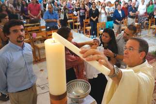 Jesuit Father David Neuhaus lights a baptismal candle during a Mass for Hebrew-speaking Catholics in Israel in 2014. 