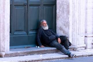 A homeless man rests outside a church in Rome, 2014. 