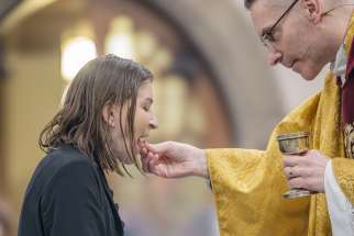 Tammy Peterson receives First Holy Communion from Fr. Peter Turrone at Holy Rosary Catholic Church in Toronto at the Easter Vigil, March 30, 2024.