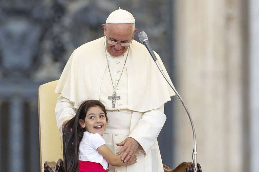 A young girl smiles as she embraces Pope Francis during an audience for families participating in the pastoral conference of the Diocese of Rome in St. Peter&#039;s Square at the Vatican June 14. 
