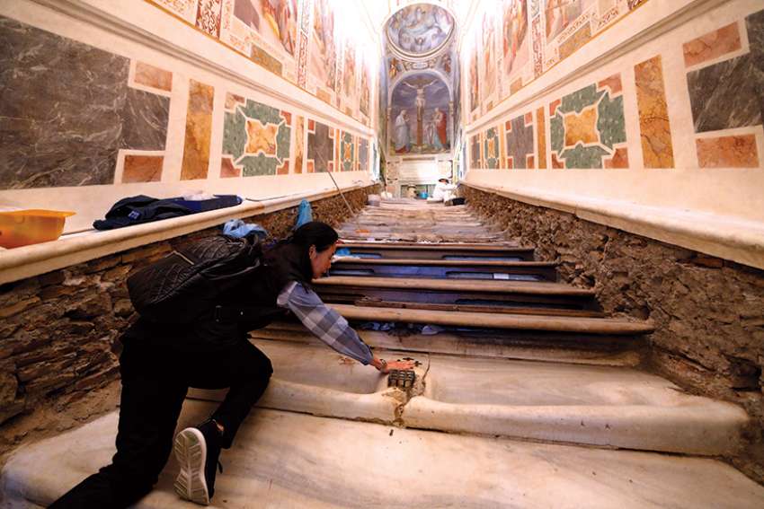 Mei Wen touches an area of the Holy Stairs where Jesus is believed to have fallen during restoration work at the Pontifical Sanctuary of the Holy Stairs in Rome. 