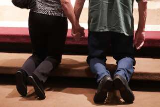 Husband and wife kneel in prayer in front of church altar. “If our child began to question his/her own sexuality, our answers would be based on biblical perspectives,” the couple wrote in an email to Alberta Child and Family Services March 6.