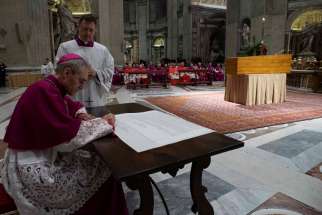 Archbishop Georg Gänswein, private secretary to Pope Benedict, signs a scroll known as a &quot;rogito&quot; to place with the body of Pope Benedict XVI in his cypress casket in St. Peter&#039;s Basilica at the Vatican Jan. 4, 2023. In addition to containing his biography, the legal document, written in Latin, also attested to his death and burial.