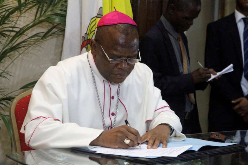 Congolese Bishop Fridolin Ambongo Besungu signs the accord between the opposition and the government of President Joseph Kabila Dec. 1 at the bishops&#039; conference in Kinshasa.