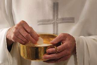 A priest prepares to distribute Communion during Mass. When we receive communion we change, little by little, into our true selves.