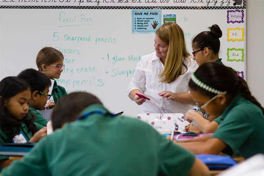A fifth-grade teacher helps her students organize their supplies on the first day of school Aug. 8 at St. Helen Catholic School in Pearland, Texas. 