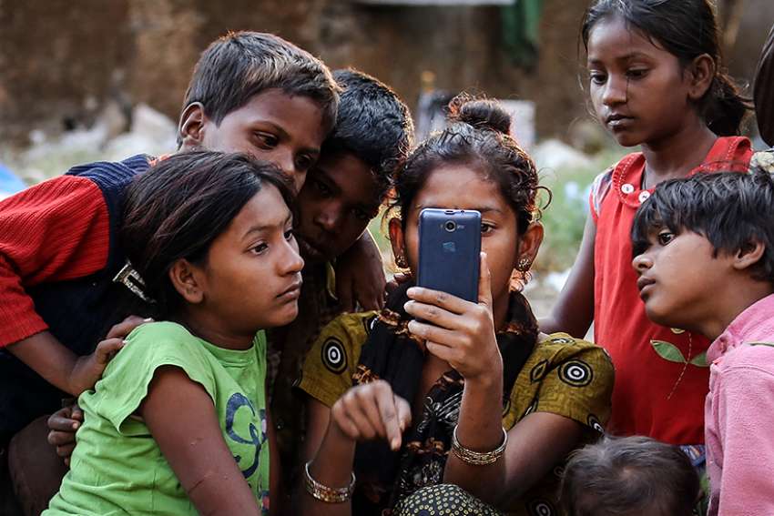Indian children watch a movie on a cellphone on the roadside in Mumbai Jan. 20, 2016. While digital communications and social media can be used as a tool of evangelization and a place of dialogue with others, they also can be lonely environments where young people fall prey to humanity&#039;s worst vices, Pope Francis wrote in his new apostolic exhortation to young people, &quot;Christus Vivit&quot; (&quot;Christ Lives&quot;). 