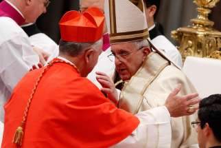 Pope Francis embraces new Cardinal John Dew of Wellington, New Zealand, after presenting the red biretta to him during a consistory at which the pope created 20 new cardinals in St. Peter&#039;s Basilica at the Vatican Feb. 14. 