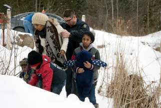 A woman and her family are taken into custody by a Royal Canadian Mounted Police officer after walking across the U.S.-Canada border at Roxham Road in Quebec.