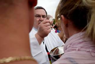 A priest in Czestochowa, Poland, distributes Communion Aug. 15, 2018, at Jasna Gora Monastery. The percentage of Catholics in the world has remained steady, while the number of priests has decreased for the first time in almost a decade, according to Vatican statistics. 