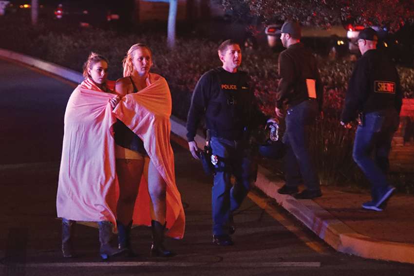 Two women draped in blankets leave the area near the Borderline Bar and Grill in Thousand Oaks, Calif., Nov. 8 after a gunman killed at least 13 people. The gunman, who opened fire without warning late Nov. 7, was found dead inside the establishment, authorities said. 