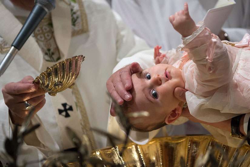 Pope Francis pours water over the head of a baby as he celebrates the baptism of 23 babies in the Sistine Chapel at the Vatican Jan. 10. The baptisms were held on the feast of the Baptism of the Lord.