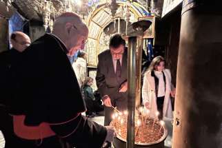 Cardinal Fernando Filoni, grand master of the Equestrian Order of the Holy Sepulchre of Jerusalem, and Ambassador Visconti di Madrone, the order&#039;s governor general, light candles at the site marking the birth of Jesus in the Church of the Nativity in Bethlehem.