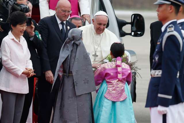 Pope Francis, accompanied by Korea&#039;s President Park Geun-hye, left, accepts flowers from children in traditional costume as he arrives in Seoul, South Korea, Aug. 14. The pope will beatify Korean martyrs and participate in the sixth Asian Youth Day durin g his five-day visit to South Korea.
