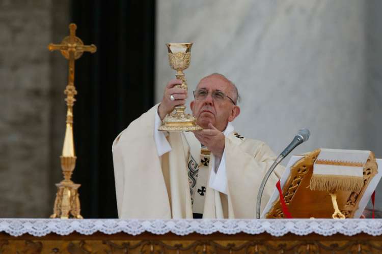 Pope Francis raises the Eucharist as he celebrates Mass marking the feast of Corpus Christi outside the Basilica of St. John Lateran in Rome May 26.