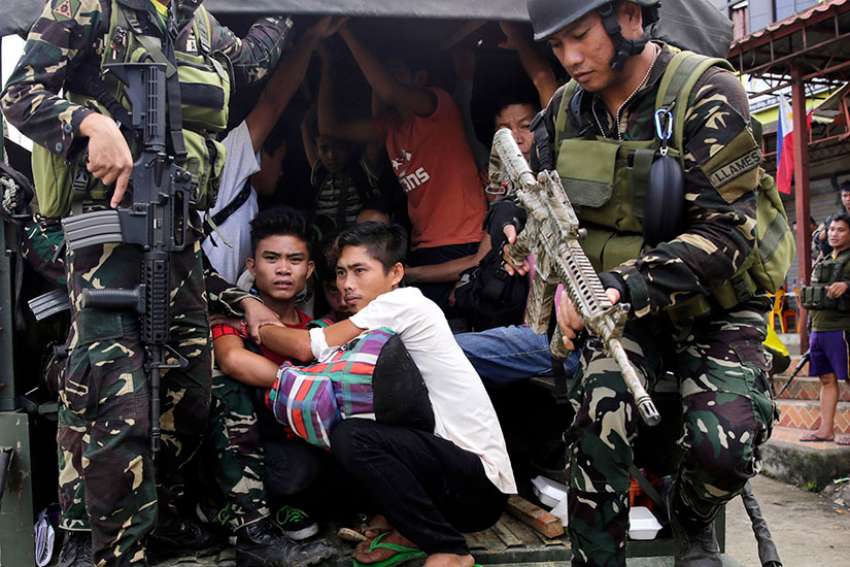 Filipino residents of Marawi are escorted to safety by government forces June 3.The Association of Major Religious Superiors in the Philippines called for an end to martial law in Mindanao, saying it was not the proper response to terrorist attacks in one city on a vast island.