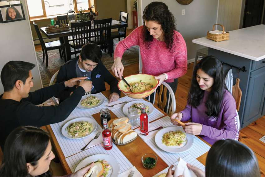 Marco Pantoja III, 18, centre, sits down for dinner with his family at their home in Valatie, N.Y. Marco will sponsor his family when they are baptized as Catholics April 3, the Easter Vigil.