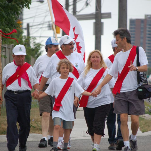 Holding the hand of his father Paul Meleca-Mazzuchin (right) and his grandfather Romeo Meleca (left) 9-year-old Zachary tries out leading the pilgrims up Islington Avenue during the first morning of the eight day journey. 