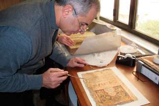 Dominican Father Najeeb Michaeel works on a manuscript at his restoration laboratory in Qaraqosh, Iraq, prior to Aug. 6. Father Michaeel and his team moved 1,300 manuscripts dating from the 14th to 19th centuries before Islamic State militants invaded Qa raqosh Aug. 6.