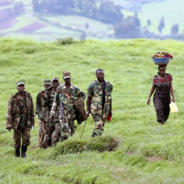 A woman walks with fighters as Congolese rebels prepare to withdraw from Mushake, near Goma, Congo, Nov. 28. As rebels initiated their partial withdrawal, Catholic organizations said the regionâ€™s civilians remained either on the run or terrified that t heir community would be the next target for a rebel attack.