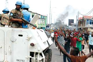 People chant slogans against Congolese President Joseph Kabila as armed UN peacekeepers watch protesters in Kinshasa. Politically-motivated attacks took place on Catholic churches in Kinshasa and area in late February, attacks Cadinal Laurent Monsengwo Pasinya calls deliberate attempts to ruin the path to peace.