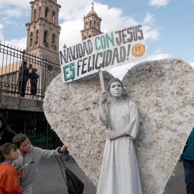Children touch the wings of a man dressed as an angel as he holds a sign reading &quot;Christmas with Jesus is happiness&quot; in Ciudad Juarez, Mexico, last year. Members of the Christian church Psalm 100 regularly dress as angels holding signs with religious messages for people to read.